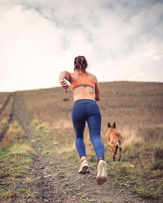 a girl running in the mountain with a German Shepherd dog