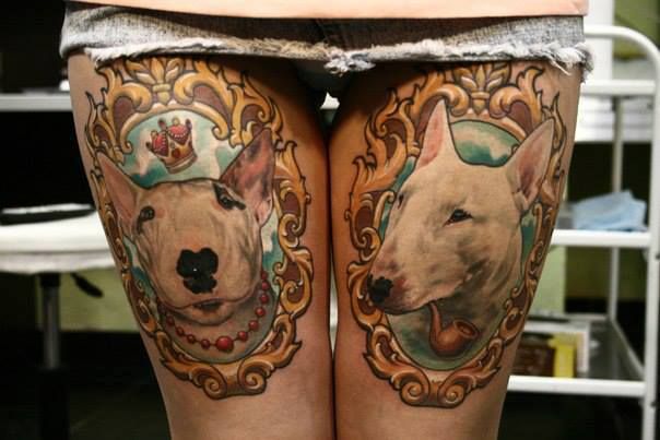 faces of English Bull Terriers in a vintage gold frame tattoo on the lap of a woman