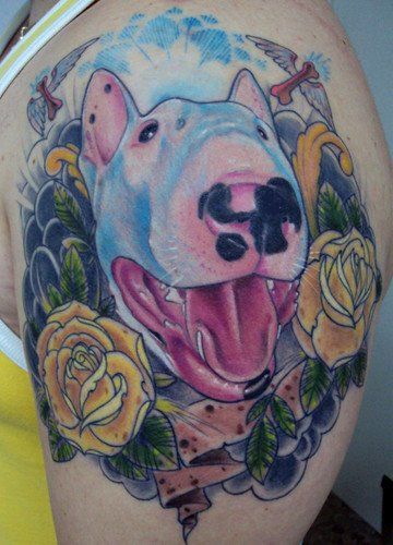 a smiling face of English Bull Terrier with flowers, leaves, clouds, and birds tattoo on the shoulder