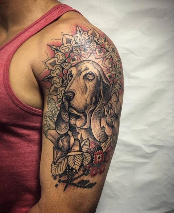 face of Basset Hound in mandala design with flowers and leaves tattoo on the shoulder