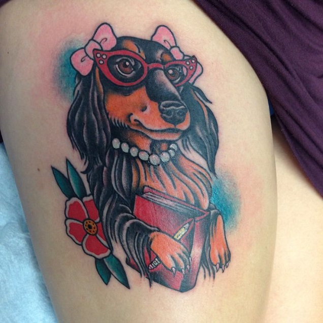 animated Dachshund wearing pink ribbons, glasses, and pearl necklace while carrying a book tattoo on thigh