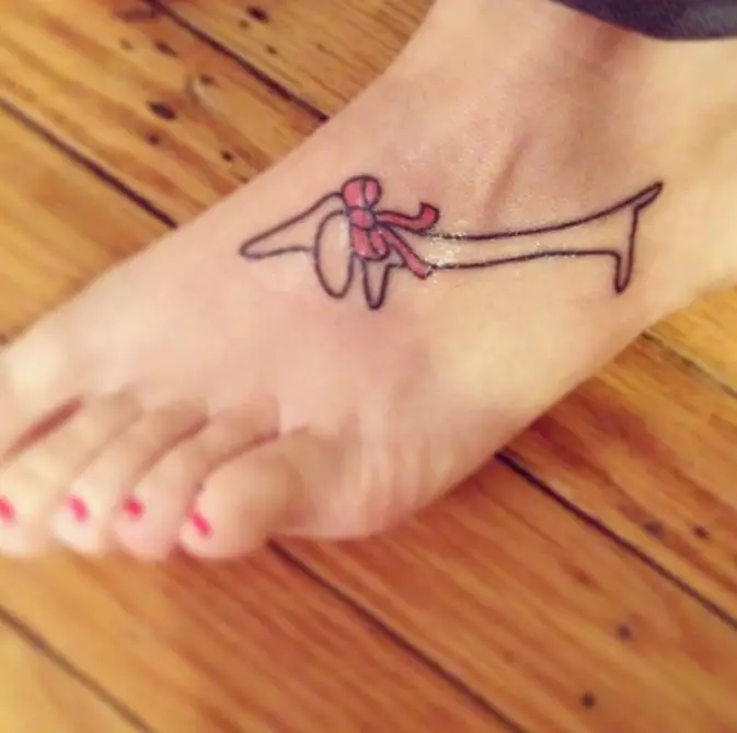 small outline of a Dachshund with pink ribbon tie tattoo on feet