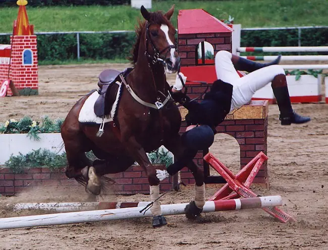 a rider falling from a jumping horse