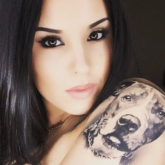 A woman with the face of a Pit Bull tattoo on her shoulder