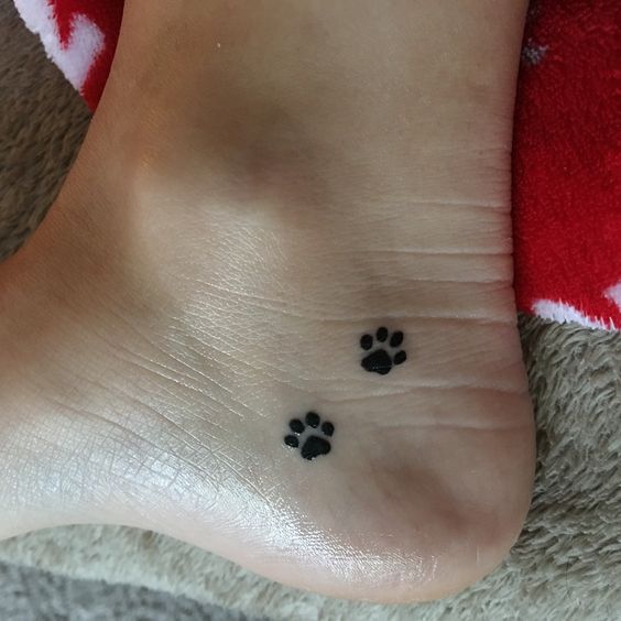 two paw print tattoos on the heel of a woman