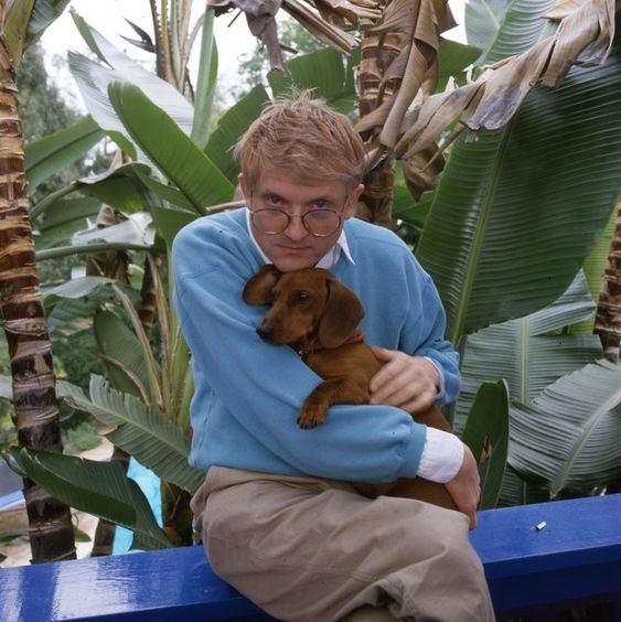 David Hockney sitting on the bench with his Dachshund