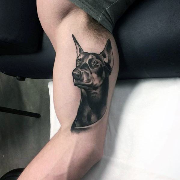 a Doberman's begging face tattoo on the biceps of a man