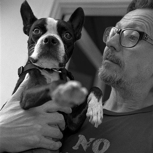 black and white photo of Gary Oldman holding his Boston Terrier