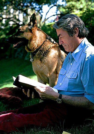 Gregory Peck reading a book beside his German Shepherd