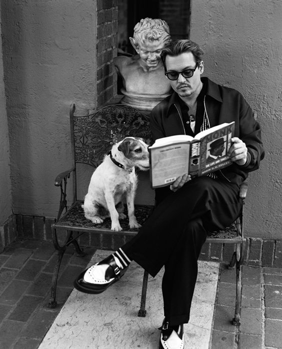 black and white photo of Johnny Depp reading a book with his Jack Russell Terrier