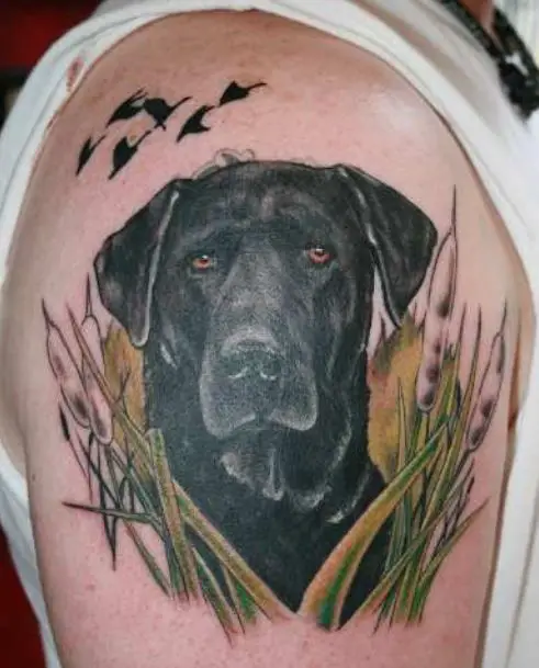 Labrador in the grass with birds above it tattoo on the shoulder