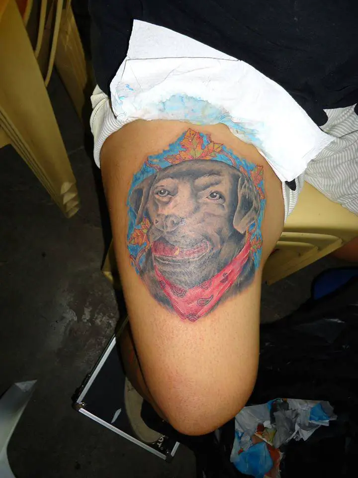 smiling face of a black Labrador tattoo on thigh