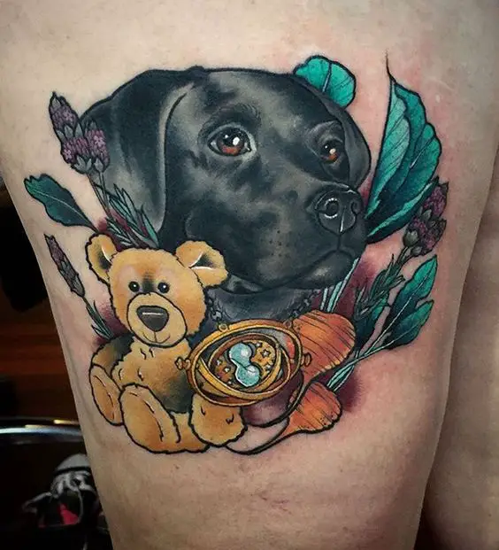 black Labrador puppy looking sideways with teddy bear, leaves, and flowers tattoo