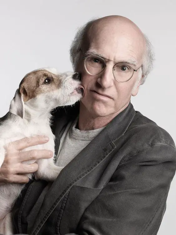 Larry David being licked on the face with his Jack Russell Terrier