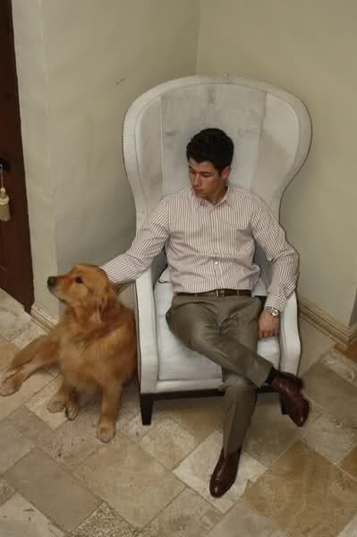 Nick Jonas siting on the chair while petting his Golden Retriever sitting next to him
