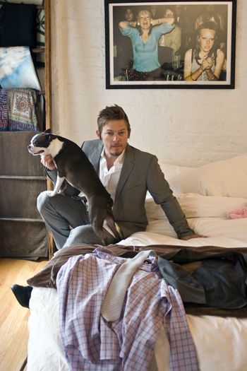 Norman Reedus sitting on the bed with his Boston Terrier leaning on his lap