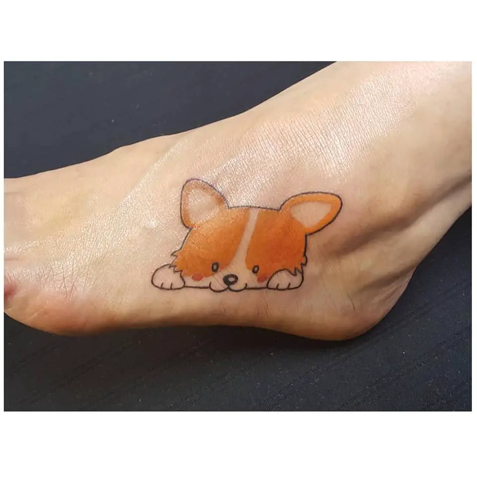 a cute lying down animated corgi tattoo on the foot