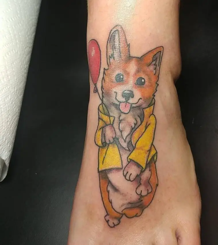 a corgi wearing a yellow jacket while holding a balloon tattoo on the foot