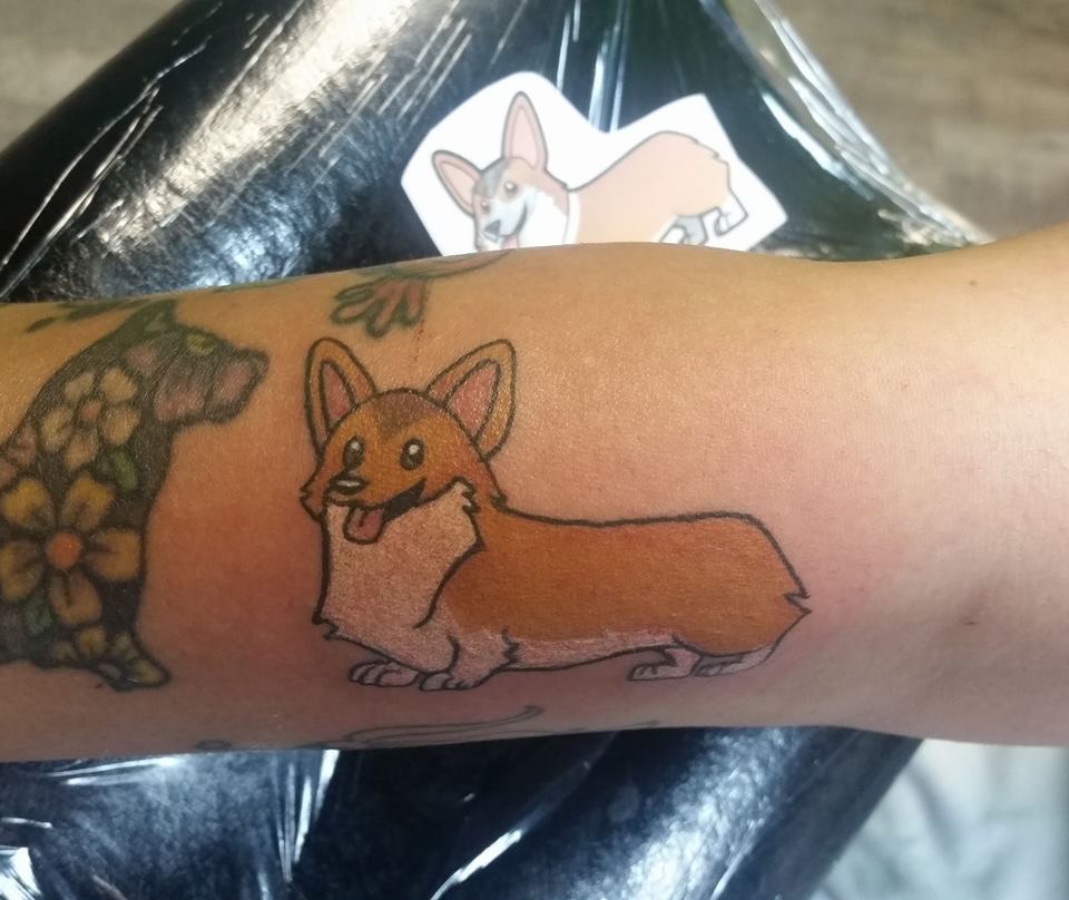 an animated corgi standing sideways tattoo on the forearm