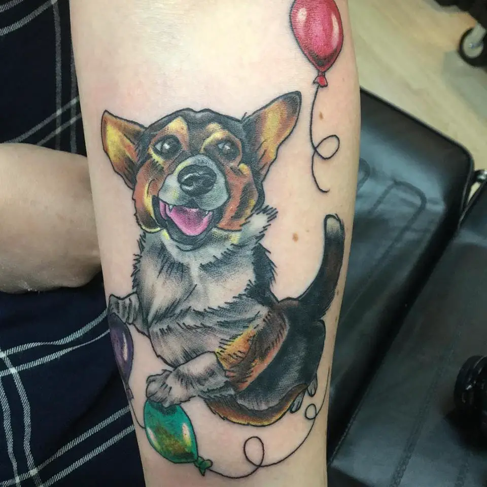 a corgi flying with balloons tattoo on the forearm