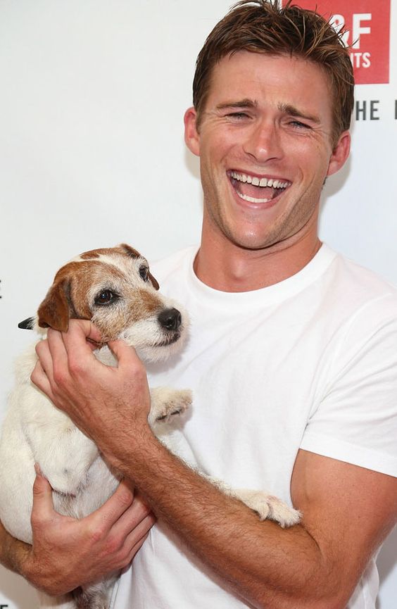 Scott Eastwood laughing while carrying his Jack Russell Terrier