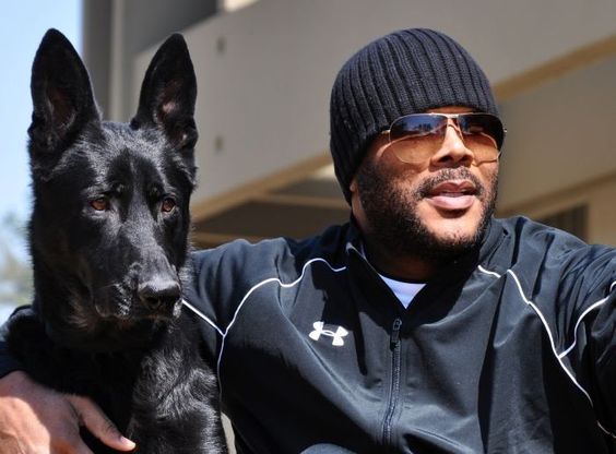Tyler Perry with his arms around his German Shepherd
