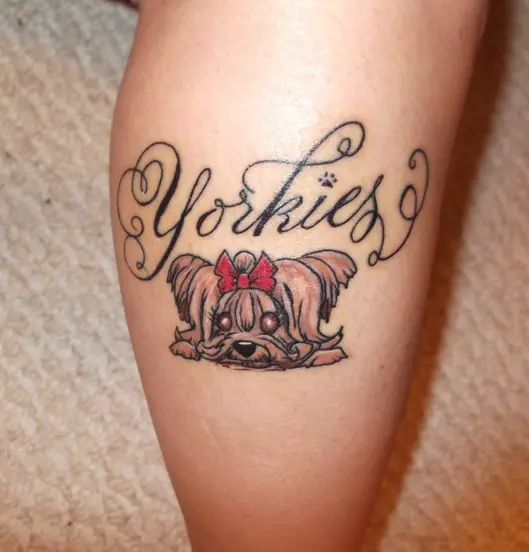 animated yorkie lying down and with written Yorkies on top of her tattoo on the leg