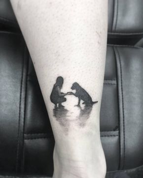 Labrador sitting in the water giving a paw to a girl tattoo on the ankle