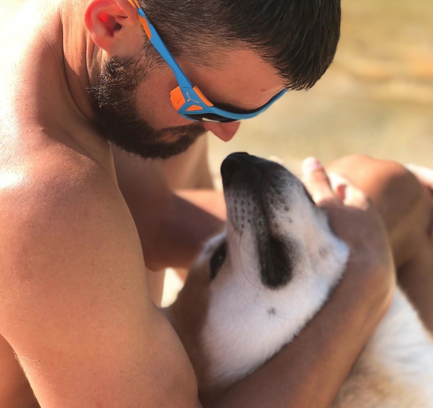 A man at the beach hugging his Akita Inu