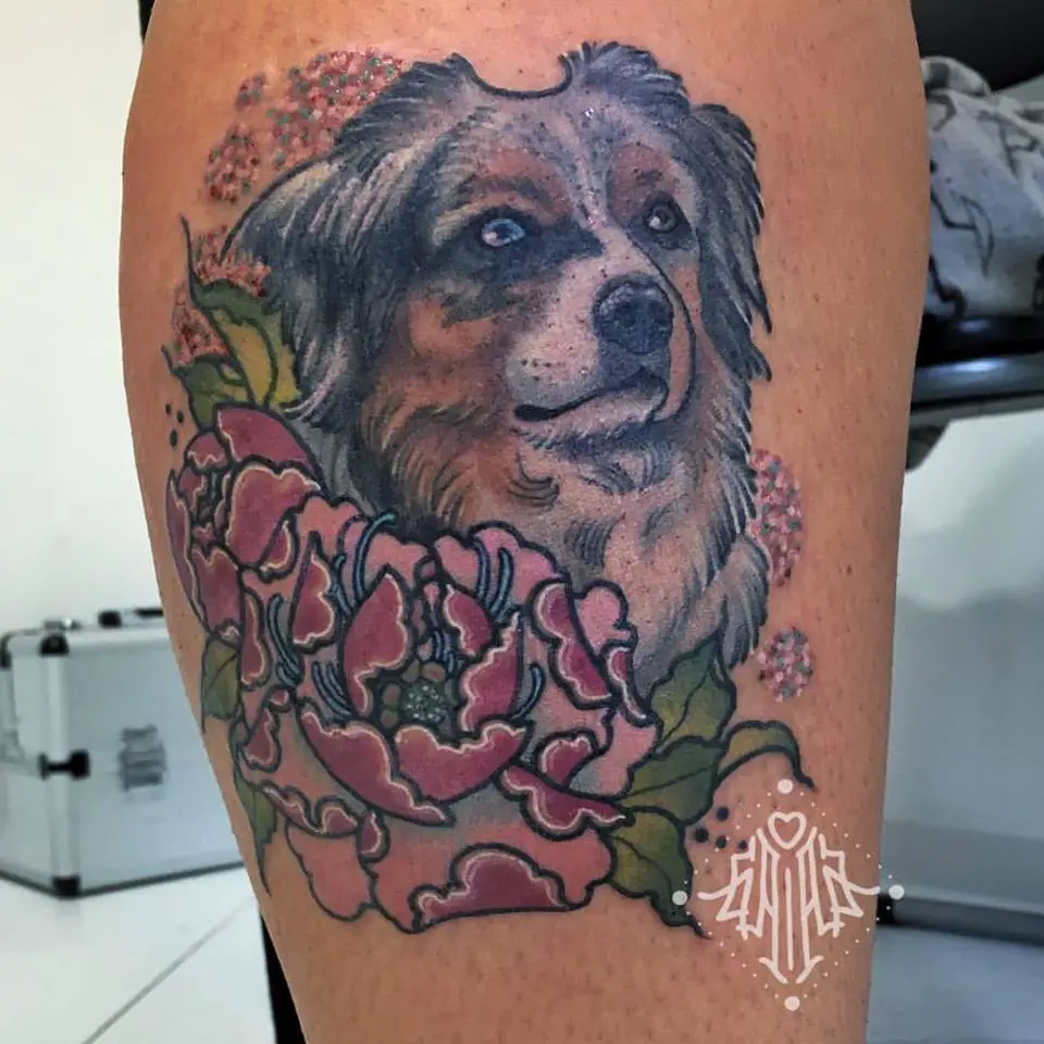 Australian Shepherd Dog with gray and brown color, surround with pink flowers tattoo on the leg
