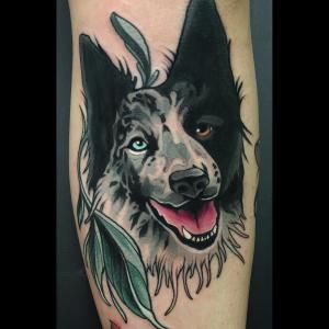 smiling face of a black and white Border Collie tattoo on the forearm