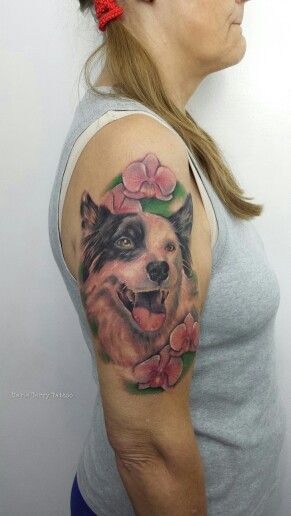A smiling face of a black and white Border Collie with flowers tattoo on the shoulder