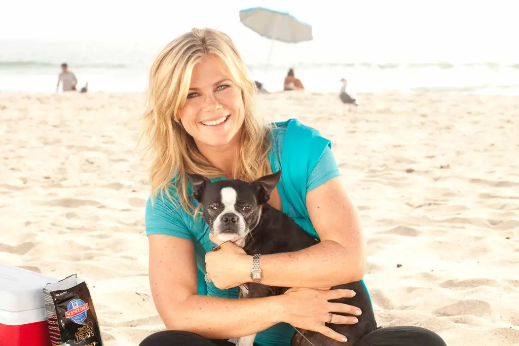 Alison Sweeny sitting at the beach with her Boston Terrier on her lap