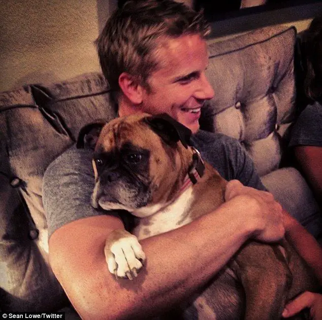 Sean Lowe sitting on the couch with his Boxer dog