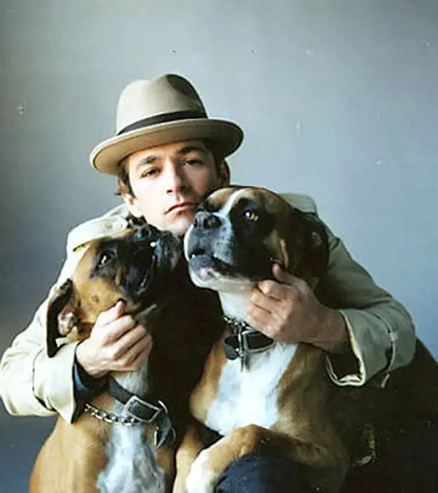 Luke Perry hugging his two Boxer dogs