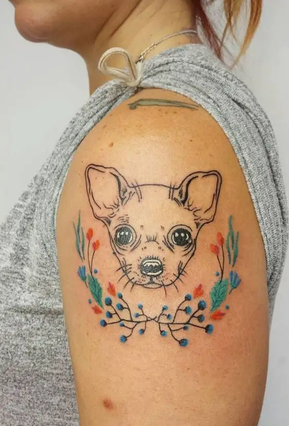outline face of Chihuahua with colorful flowers around tattoo on the shoulder