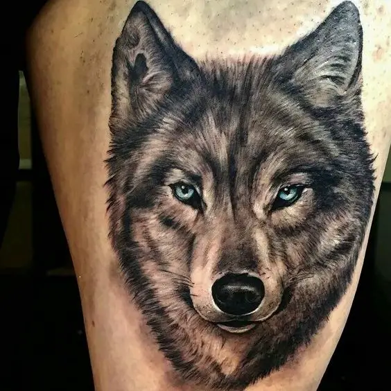 face of a black and gray Husky with blue eyes tattoo on the thigh