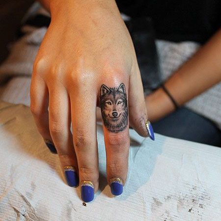 pointing finger of a woman with the face of a Husky tattoo