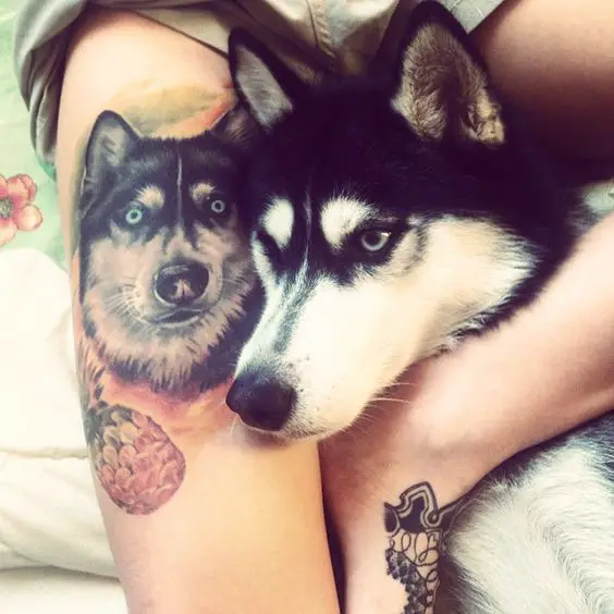 face of a Husky next to a girl's thigh with the tattoo of its face