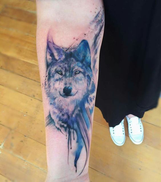 beautiful face of a Husky colored with blue watercolor tattoo on the forearm