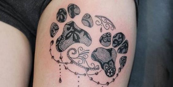 paw prints with mandala design tattoo on the thigh of a woman