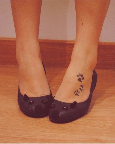 three small paw prints tattoo on the foot of the woman