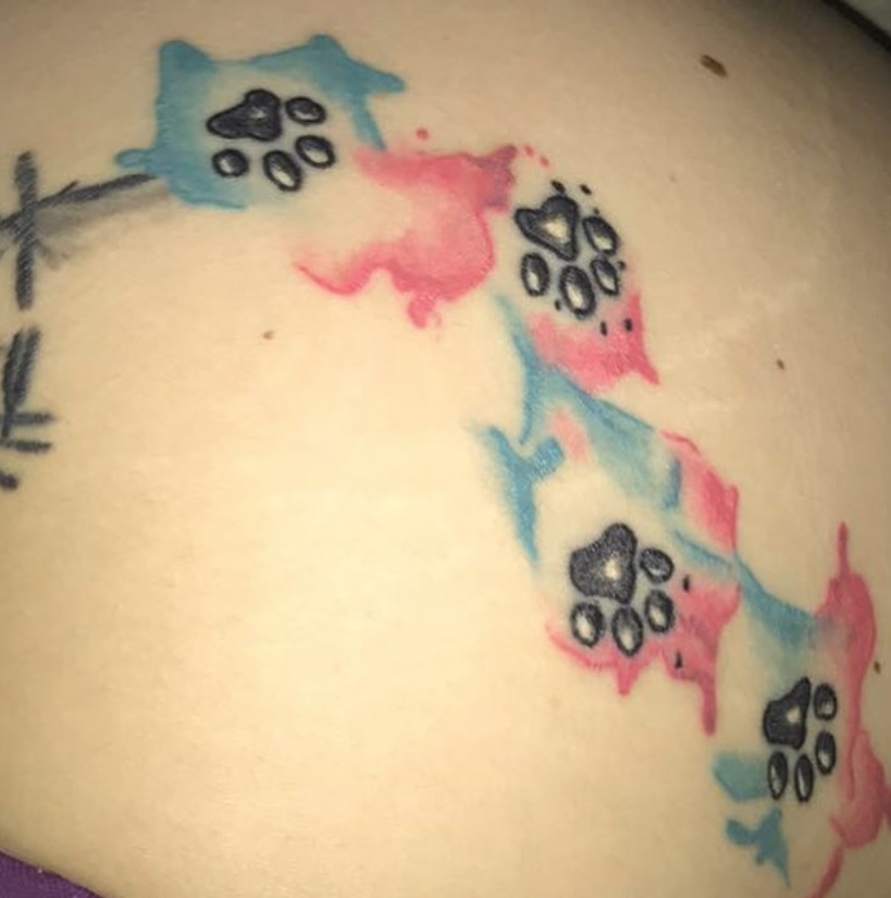 four small paw prints with blue and pink water color background design tattoo