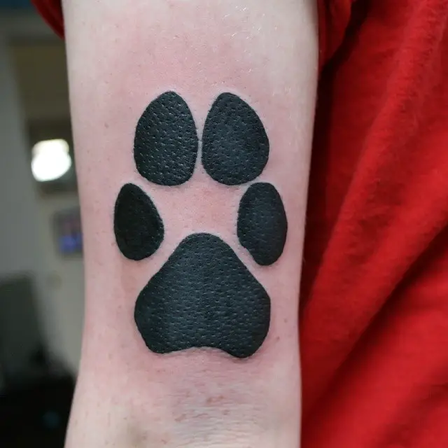 a large paw print tattoo on the triceps of the person
