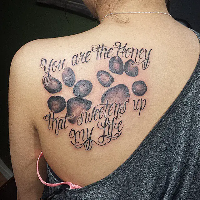 large paw print with quote - You are the honey that sweetens up my life tattoo on the back of the woman