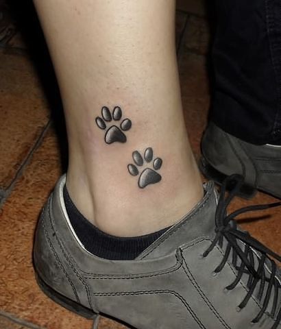 two paw print tattoo on the ankle of the woman