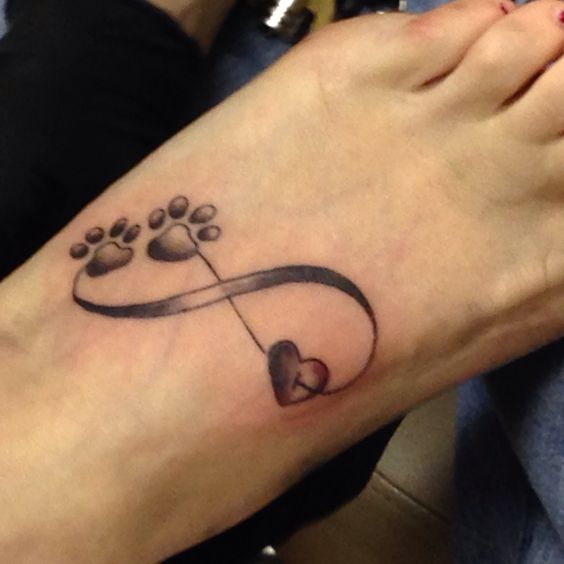 infinity sign with two paw prints tattoo on the foot of a woman
