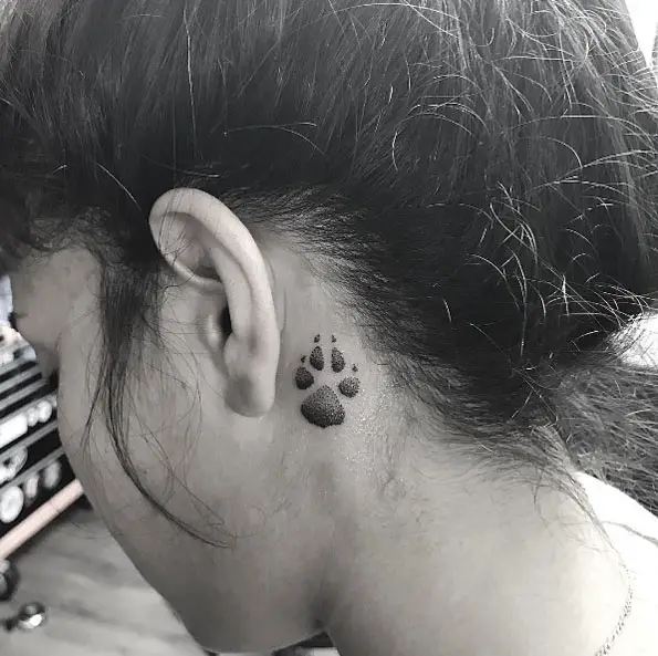 a black paw print tattoo on the back of the ear of the woman