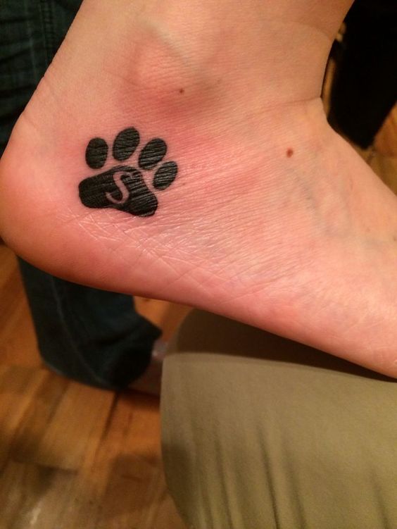 a paw print with S initial inside tattoo on the heel of the woman