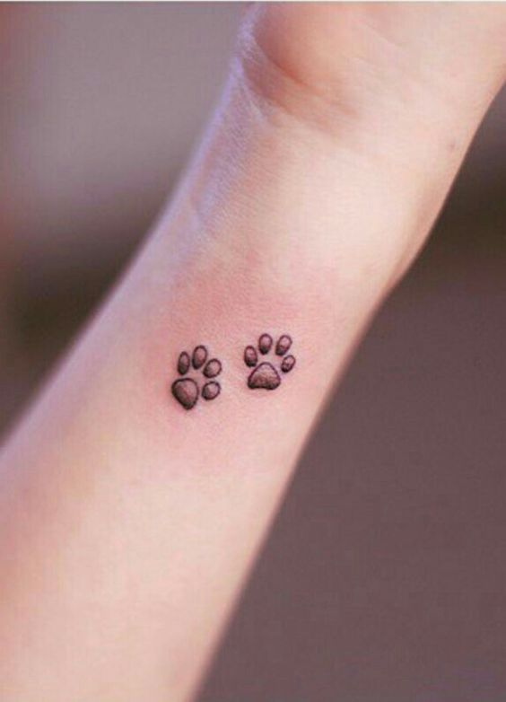 two small paw print tattoo on the wrist of the woman